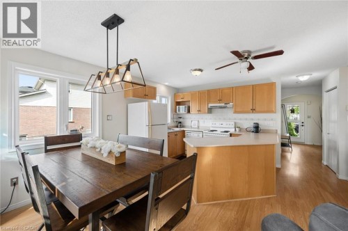 Open-concept living space featuring wood-finish flooring, a kitchen with light wood cabinetry, a breakfast bar, and white appliances - 67 Apple Tree Drive, Kitchener, ON 