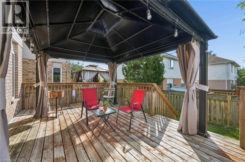 Wood-finish deck with a black gazebo featuring light-toned fabric privacy curtains - 67 Apple Tree Drive, Kitchener, ON 