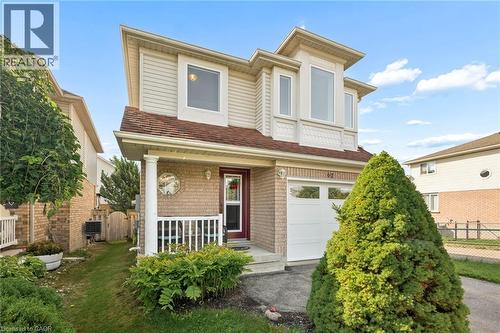 Brick and siding exterior with a covered porch, white column, and an attached garage with a white door - 67 Apple Tree Drive, Kitchener, ON 