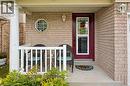 Brick exterior with a covered porch featuring a white column, white railing, and an octagonal window - 67 Apple Tree Drive, Kitchener, ON 