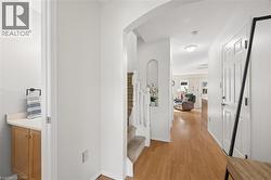 Wood-finish flooring throughout, arched entryway, staircase with white spindles, built-in wall niche, and panel interior door - 