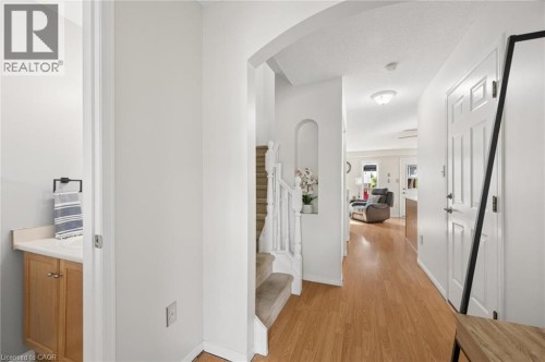 Wood-finish flooring throughout, arched entryway, staircase with white spindles, built-in wall niche, and panel interior door - 67 Apple Tree Drive, Kitchener, ON 