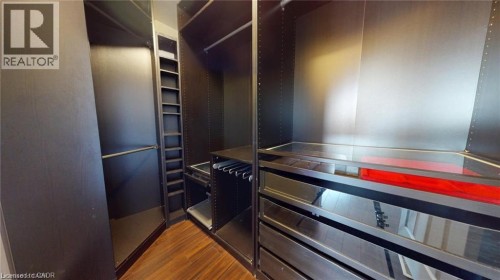 Built-in custom closet system featuring dark wood-finish cabinetry, extensive shelving, hanging rods, and integrated drawers with reflective panels - 11 Sorrento Street, Kitchener, ON 