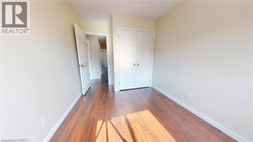Wood-finish flooring, light-toned walls, and a bi-fold closet door - 11 Sorrento Street, Kitchener, ON 