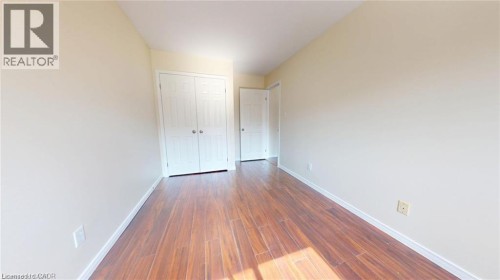Wood-finish flooring with light-toned walls and trim, featuring a built-in closet with bi-fold doors - 11 Sorrento Street, Kitchener, ON 