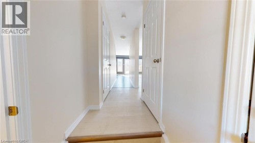 Hallway with light-colored tile flooring, white interior doors, and a wood-finish step - 11 Sorrento Street, Kitchener, ON 