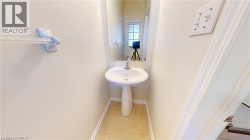 Pedestal sink with chrome faucet, wall-mounted mirror, and wood-finish flooring - 11 Sorrento Street, Kitchener, ON 