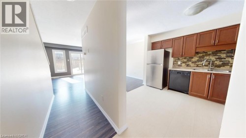 Kitchen featuring wood-finish cabinetry, stainless steel refrigerator, black dishwasher, and a tile backsplash - 11 Sorrento Street, Kitchener, ON 