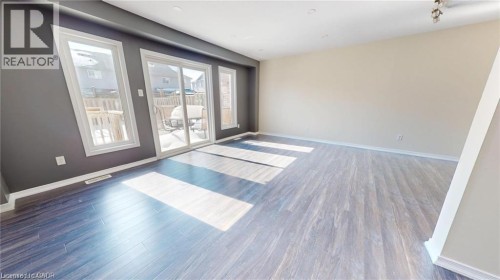Wood-finish flooring, sliding glass patio door, multiple windows, and light-toned walls - 11 Sorrento Street, Kitchener, ON 