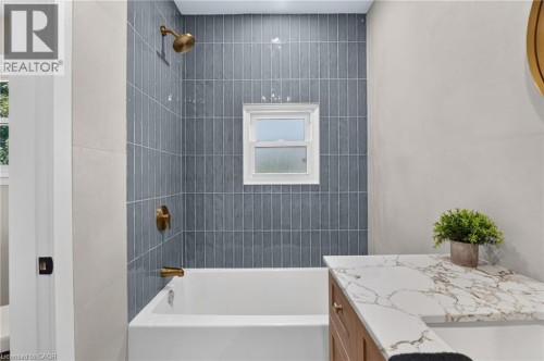 Tub and shower combination with vertical tile surround and brass fixtures - 43 Brucedale Avenue E, Hamilton, ON 