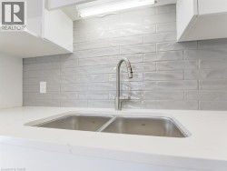 Stainless steel double basin sink set into a white countertop, complemented by a contemporary brushed nickel faucet - 