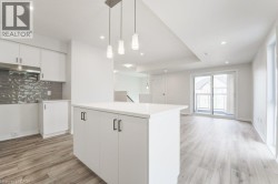 Kitchen featuring white cabinetry, a central island with a solid surface countertop, textured tile backsplash, and a pendant light fixture - 