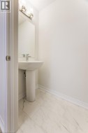 Pedestal sink with a chrome faucet, large vanity mirror, two-light fixture, and tile flooring - 