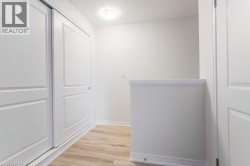 White panel sliding closet doors, wood-finish flooring, white walls, and a flush mount ceiling light - 
