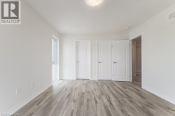 Light wood-finish flooring, white walls, double closet doors, single window, and a flush mount ceiling light - 