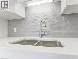Stainless steel double basin sink set into a white countertop, complemented by a contemporary brushed nickel faucet - 