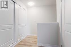 White panel sliding closet doors, wood-finish flooring, white walls, and a flush mount ceiling light - 