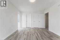 Light wood-finish flooring, white walls, double closet doors, single window, and a flush mount ceiling light - 
