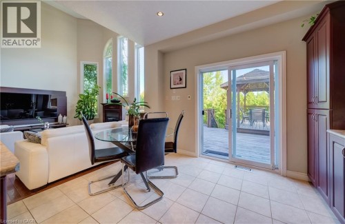 Soaring ceiling with recessed lighting, prominent arched and vertical windows, fireplace feature, built-in cabinetry, and sliding glass door leading to an exterior deck with a gazebo - 573 Robert Ferrie Drive, Kitchener, ON 