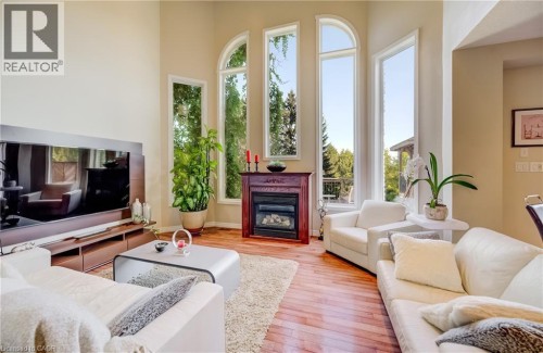 Vaulted ceiling with a wood-finish floor, a gas fireplace with a wood mantel, and tall arched windows - 573 Robert Ferrie Drive, Kitchener, ON 