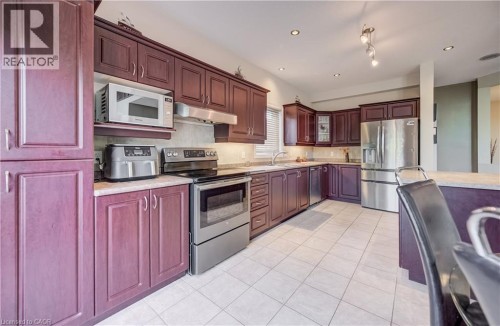 Kitchen featuring extensive cabinetry, stainless steel appliances, tile flooring, recessed lighting, and under-cabinet lighting - 573 Robert Ferrie Drive, Kitchener, ON 