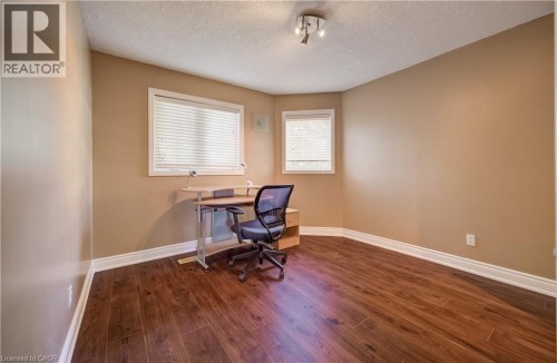 Wood-finish flooring with white trim, two windows with blinds, and ceiling-mounted track lighting - 573 Robert Ferrie Drive, Kitchener, ON 