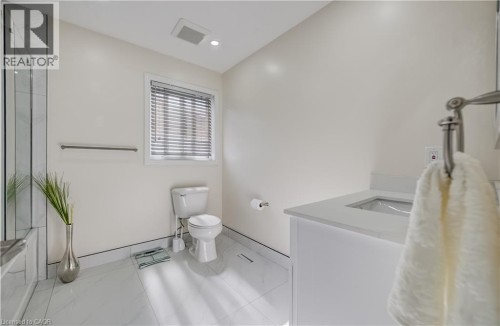 White vanity with integrated sink, white tiled flooring, and a window with blinds - 573 Robert Ferrie Drive, Kitchener, ON 