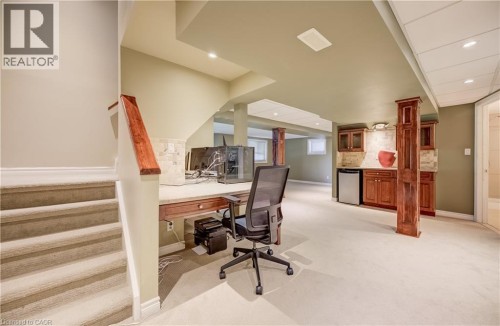 Finished lower level featuring recessed lighting, built-in cabinetry, a beverage refrigerator, and a dedicated workspace - 573 Robert Ferrie Drive, Kitchener, ON 