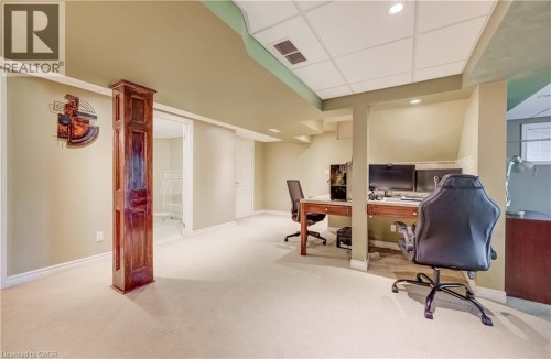Recessed lighting, drop ceiling, carpeted flooring, wall-mounted desk area, and a wood-paneled support column - 573 Robert Ferrie Drive, Kitchener, ON 