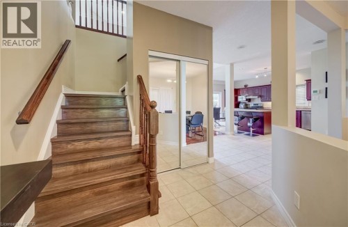 Hardwood stairs with a classic wood banister, mirrored closet doors, and tile flooring - 573 Robert Ferrie Drive, Kitchener, ON 