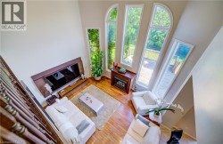 Two-story ceiling, multiple arched and rectangular windows, wood-finish flooring, built-in fireplace, and a deck - 