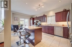Kitchen featuring wood-finish cabinetry, tile flooring, stainless steel appliances, a center island with a countertop, and recessed lighting - 