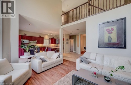 Hardwood-style flooring in the living area, open-concept kitchen with dark wood-finish cabinetry, stainless steel appliances, and recessed lighting - 573 Robert Ferrie Drive, Kitchener, ON 