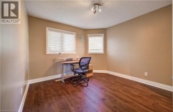 Wood-finish flooring with white trim, two windows with blinds, and ceiling-mounted track lighting - 