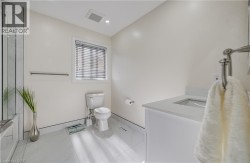 White vanity with integrated sink, white tiled flooring, and a window with blinds - 
