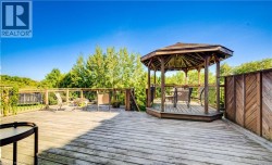 Expansive wood deck with a built-in gazebo, wood railing, and privacy panel - 