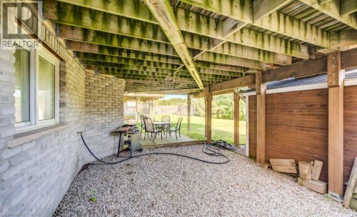 Covered outdoor area with gravel flooring, exposed wood beam ceiling, and a brick exterior wall - 573 Robert Ferrie Drive, Kitchener, ON 