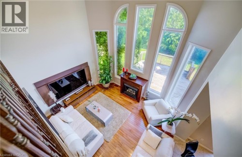Two-story ceiling, multiple arched and rectangular windows, wood-finish flooring, built-in fireplace, and a deck - 573 Robert Ferrie Drive, Kitchener, ON 