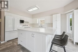 White shaker cabinetry, light-toned countertops, stone-finish flooring, recessed lighting, and a kitchen island - 