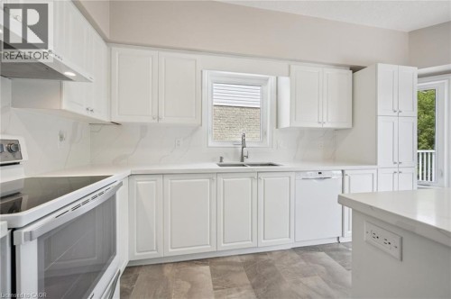 White shaker-style cabinetry with chrome hardware, full-height quartz backsplash, stainless steel sink with gooseneck faucet, integrated dishwasher, and wood-finish flooring - 426 Hidden Creek Drive, Kitchener, ON 