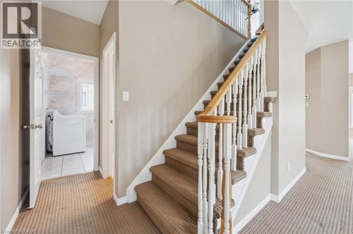 Carpeted staircase with white balusters and a wood-finish handrail - 426 Hidden Creek Drive, Kitchener, ON 