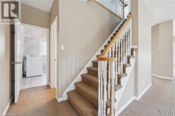 Carpeted staircase with white balusters and a wood-finish handrail - 