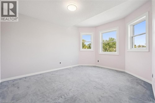 Recessed ceiling light fixture, three windows with white trim, light-colored wall paint, and gray carpet flooring - 426 Hidden Creek Drive, Kitchener, ON 
