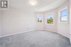 Recessed ceiling light fixture, three windows with white trim, light-colored wall paint, and gray carpet flooring - 