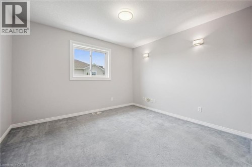 Carpeted room with a double-pane window, flush-mount ceiling light, and two wall sconces - 426 Hidden Creek Drive, Kitchener, ON 