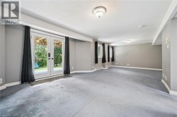 Expansive lower-level space featuring light gray walls, plush gray carpeting, and multiple windows - 