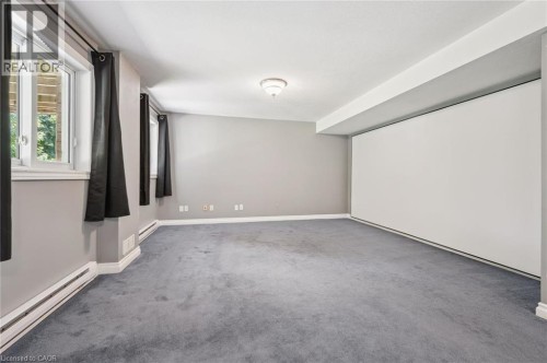 Carpeted room featuring multiple windows, a ceiling-mounted light fixture, and a large built-in white panel - 426 Hidden Creek Drive, Kitchener, ON 
