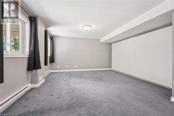 Carpeted room featuring multiple windows, a ceiling-mounted light fixture, and a large built-in white panel - 