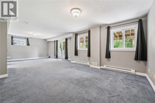 Spacious room featuring gray carpet flooring, multiple windows, a double glass door, and flush-mount ceiling lights - 426 Hidden Creek Drive, Kitchener, ON 