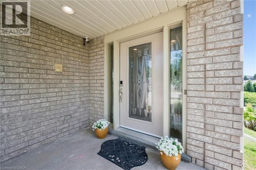 Brick exterior with a recessed entryway, featuring a panel-inlaid door with decorative glass, and a side light - 426 Hidden Creek Drive, Kitchener, ON 